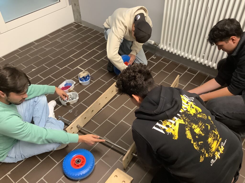 Vier Schüler bauen gemeinsam eine Seifenkiste zusammen.