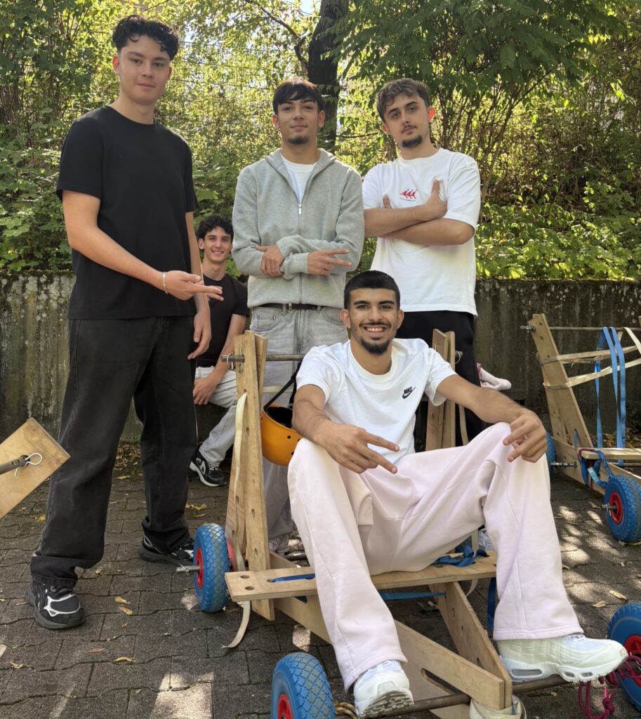 Fünf Schüler posieren gemeinsam mit ihrer selbst gebauten Seifenkiste.